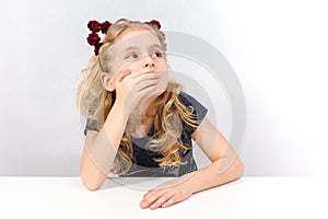 Amazed little girl sitting at table