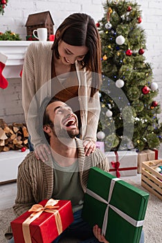 amazed man holding presents near wife