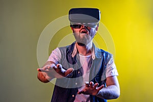 Amazed man standing in virtual reality headset, playing video game and trying to touch something.