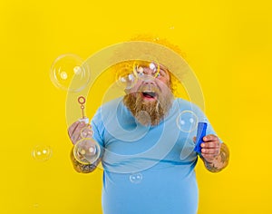 Amazed man with yellow wig in head play with bubbles soap