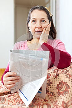 Amazed mature woman with newspaper