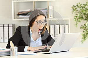 Amazed office worker reading good news in a computer