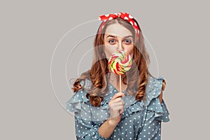 Amazed pinup girl ruffle blouse licking sweet candy looking at camera, eating delicious confectionery lollipop