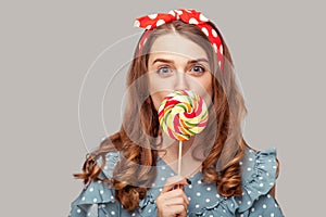 Amazed pinup girl ruffle blouse licking sweet candy looking at camera, eating delicious confectionery lollipop with surprised