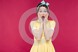 Amazed pinup girl in yellow dress standing with mouth opened