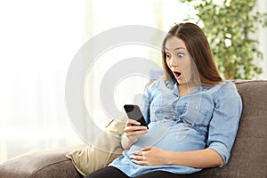 Amazed pregnant woman looking at smart phone