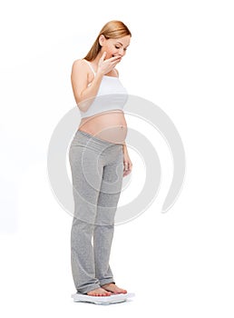 Amazed pregnant woman weighting herself
