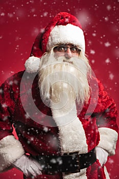 Amazed santa claus standing with hands on waist while snowing