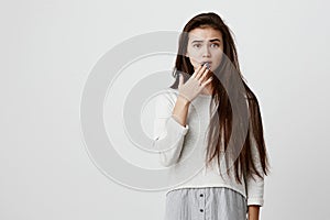 Amazed shocked female model with straight dark hair, wearing casual clothes, looking with bugged eyes and bewilderment