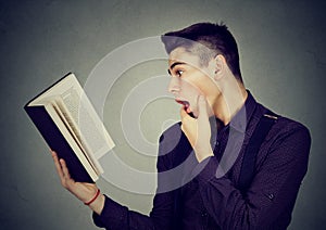 Amazed shocked man reading a book