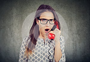 Amazed shocked woman talking on a telephone