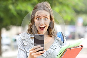 Amazed student checking smart phone news in the street