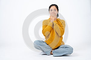 An amazed and stunned young Asian woman is covering her mouth, feeling shocked and surprised