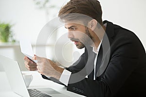 Amazed surprised businessman in suit shocked by reading mail let