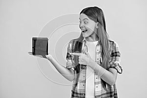 amazed teen girl shopping with present in studio. teen girl holding shopping box on background. teen girl after