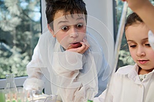 Amazed teenage boy watching with stupefaction a chemical reaction taking place while conducting experiment at chemistry