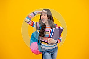 Amazed teenager. Schoolchild, teenage student girl hold book on yellow isolated studio background. School and education