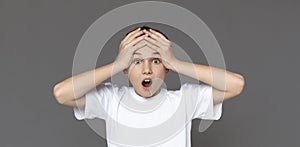 Amazed teenager screaming, holding head, grey background