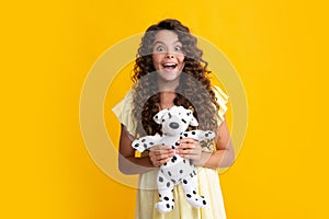 Amazed teenager. Teen girl in casual clothes hold soft toy for birthday on yellow background. Kid spending time with her