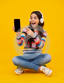 Amazed teenager. Teenage girl with smart phone. Portrait of teen child using mobile phone, cell web app. Kid showing