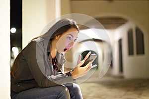 Amazed woman checking phone in the night