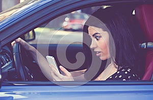 Amazed woman distracted reading a message on cellphone driving a car