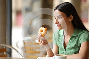 Amazed woman eating delicious doughnut in a bar photo