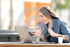 Amazed woman finding online content on laptop in a park