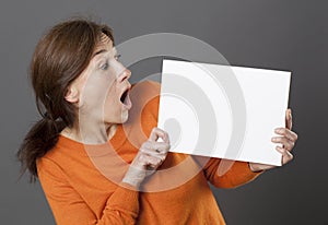 Amazed woman holding a panicking blank communication board to alert