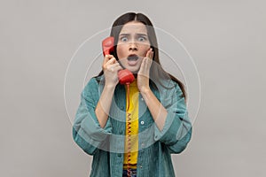 Amazed woman holding phone handset surprised by conversation open mouth shocked by unbelievable news