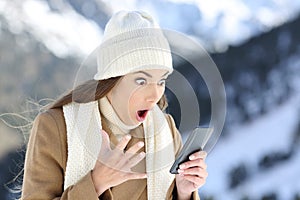 Amazed woman reading on line news in winter