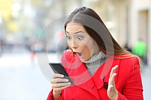 Amazed woman reading news on line in a phone