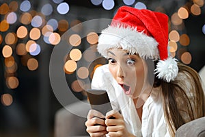 Amazed woman reading phone content in christmas