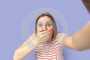 Amazed woman taking selfie picture, covering mouth with palm, point of view, making selfportrait.