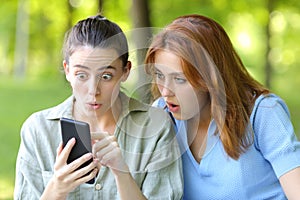 Amazed women checking phone content in a park