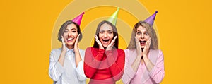 Amazed women in party hats in studio