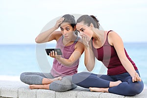 Amazed women watching yoga tutorial on the beach