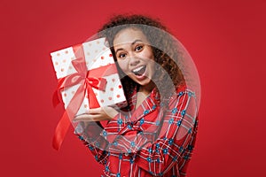 Amazed young african american girl in pajamas homewear posing resting at home isolated on red background. Relax good