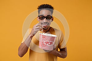 Amazed young african american guy in 3d imax glasses posing isolated on yellow orange background in studio. People photo