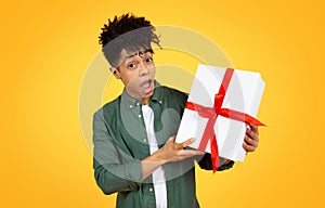 Amazed young african american guy holding gift box photo