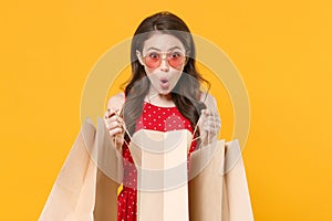 Amazed young brunette woman girl in red summer dress, eyeglasses posing isolated on yellow wall background studio