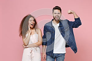 Amazed young couple two friends european guy african american girl in casual clothes isolated on pastel pink background