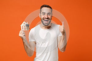Amazed young man in casual white t-shirt posing isolated on orange background studio portrait. People lifestyle concept