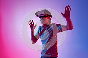 Amazed young man using a virtual reality headset playing video games trying to touch something with hand