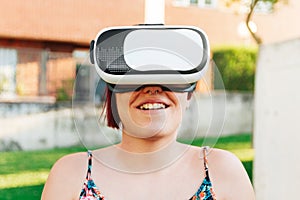 Amazed young woman experiencing virtual reality in VR headset outdoors