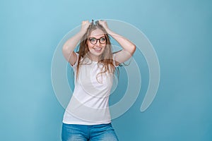 Amazed young woman holding her hands behind her head in a white sweatshirt