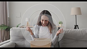 Amazed young woman opening cardboard box with internet store order.