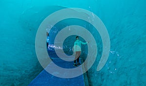 Amazed young woman touches the smooth walls of ice inside famous Mer De Glace.