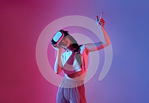 Amazed young woman using a virtual reality headset playing video games trying to touch something with hand