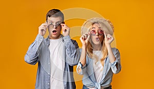 Amazed youngsters wearing trendy sunglasses and looking at camera